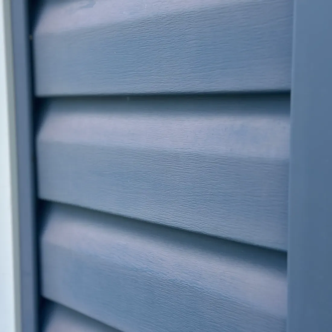 Before — Oxidation removal — the chalky UV haze dissolved and hand-brushed off, the original blue back. Same siding, no paint.