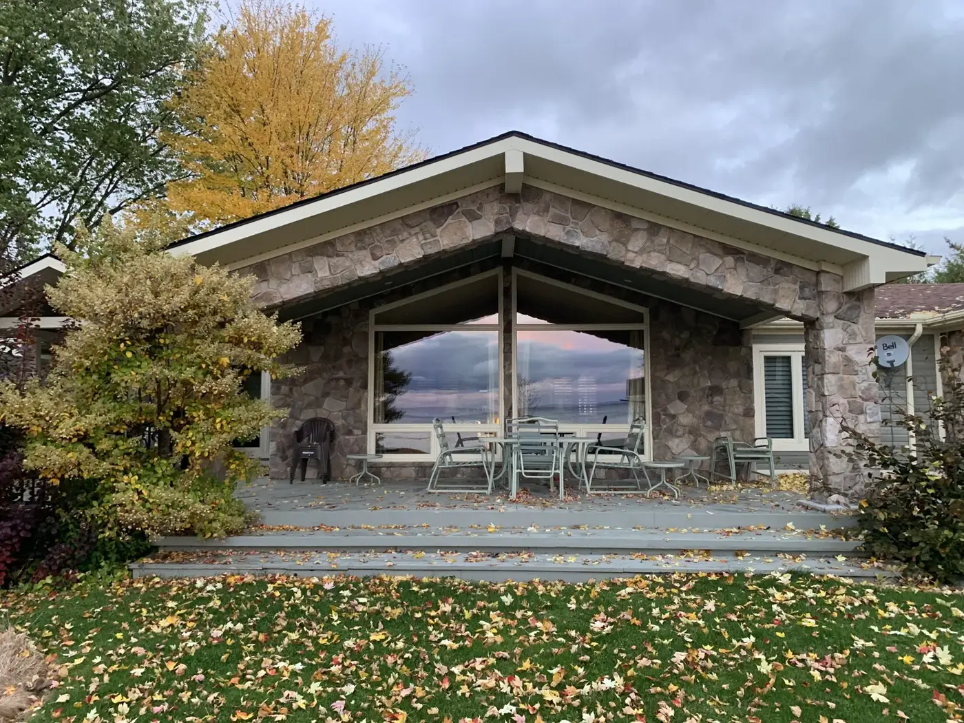 A stone Lake Simcoe waterfront home in Orillia with freshly cleaned picture windows reflecting the evening sky — exterior care by Nord